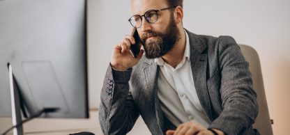 Young business man talking on phone and working on computer